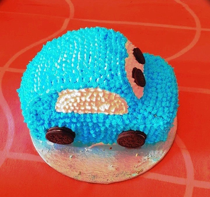 Hand-sculpted blue buttercream car cake with Oreo cookie wheels